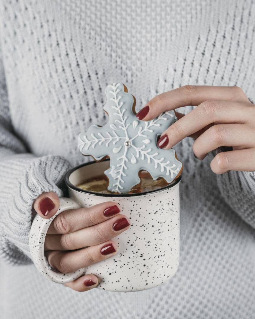 high-angle-woman-dipping-snowflake-cookie-hot-chocolate